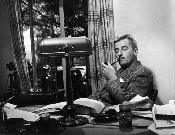 William Faulkner enjoying a smoke in his study.