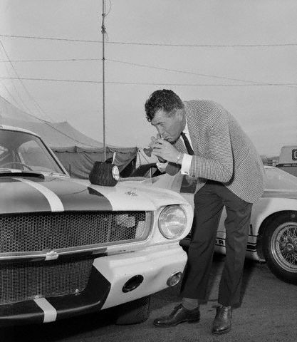 Carroll Shelby, whose Ford powered cars have been a constant contender in International racing, plays a toy flute to charm a toy Cobra out of its basket on the hood of his latest offering to the automotive world, the Mustang GT 350, at the first showing of the car- January 27th, 1965 in Riverside, CA.  The Shelby is a modified Ford Mustang Fastback, with a 289 Ford Cobra engine, front disc brakes, and improved suspension for road racing or high speed driving. -- Image by © Bettmann/CORBIS